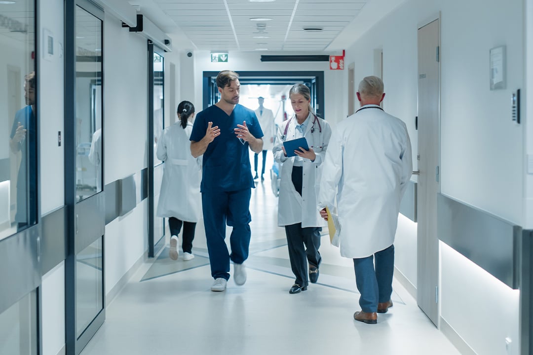 doctors-studying-tablet-device-walking-medical-center-hallway