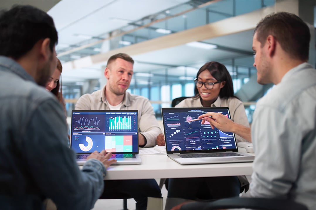 executives-in-meeting-at-conference-table-studying-dats-on-laptop-screens