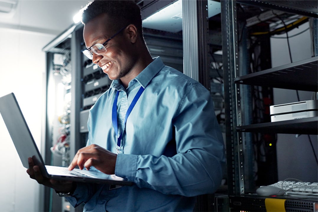 smiling-IT-tech-on-laptop-in-data-center-CASCADING