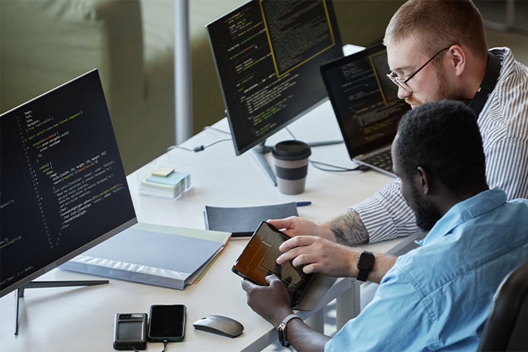 two-men-at-workstations-reading-data-on-mobile-device-CASCADING